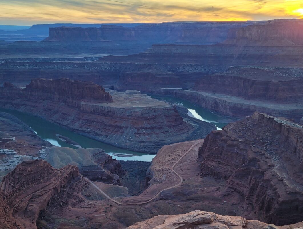 Stunning sunset over Dead Horse Point State Park with vivid orange and pink skies reflecting in the Colorado River below.